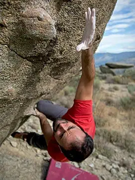 Imagen de persona escalando una roca.