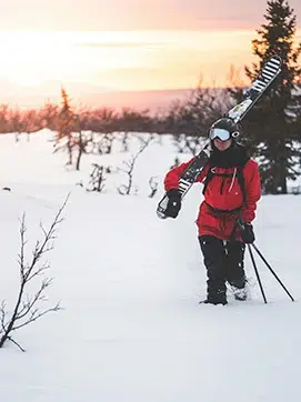 persona caminando en la nieve con material de esquí