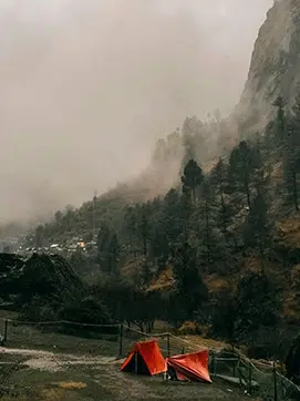 Paisaje montañoso y verde con tienda de campaña en el centro.