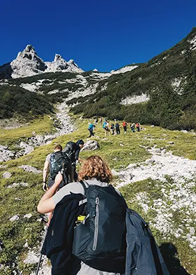 personas haciendo trekking direccion a la montaña