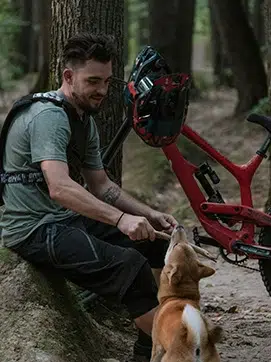 una persona con su perro en el centro de la anturaleza acompañado por su bicicleta de montaña