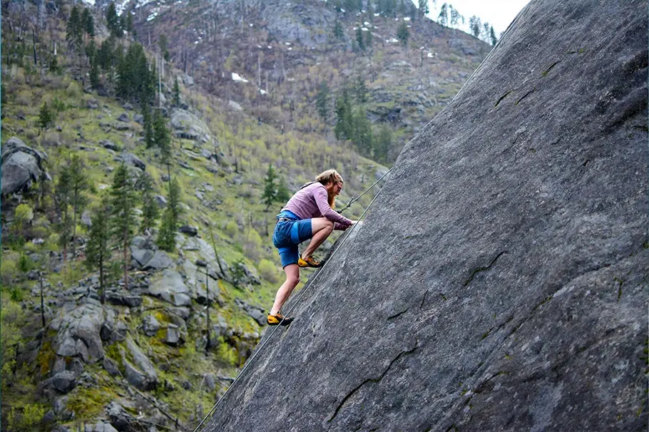 Imagen que muestra un paisaje de naturaleza y una persona escalando una pared